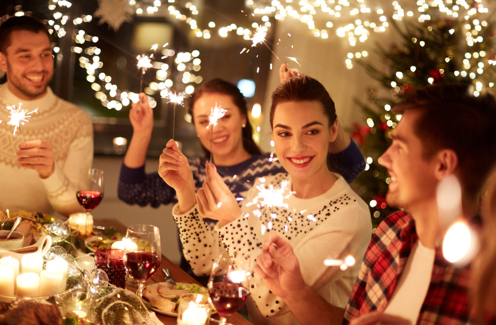 happy-young-adult-friends-celebrating-Christmas-with-sparklers-at-home-feast